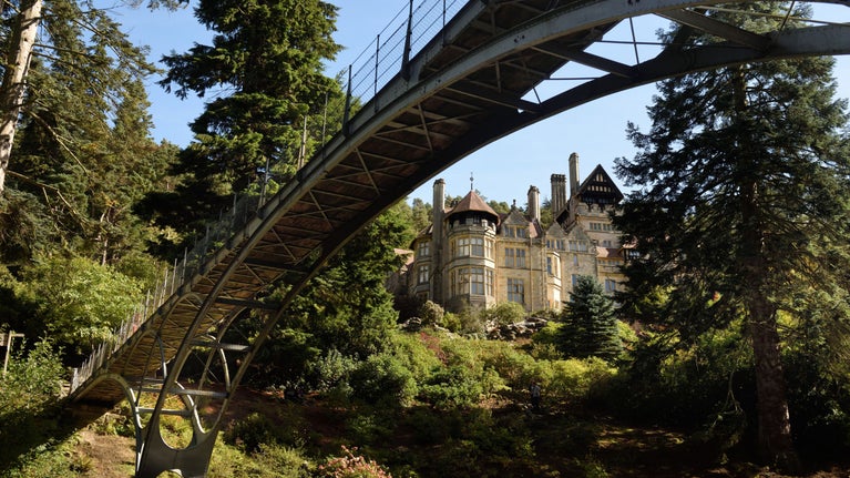 Cragside House framed under the grand arch of Cragside's industrial Iron Bridge.